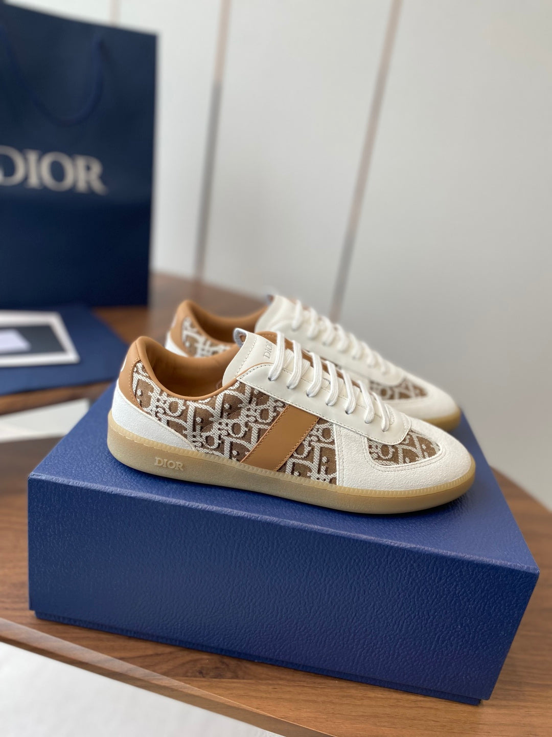 Side view Dior unisex sneakers in white with tan patterned quarter panel and laces