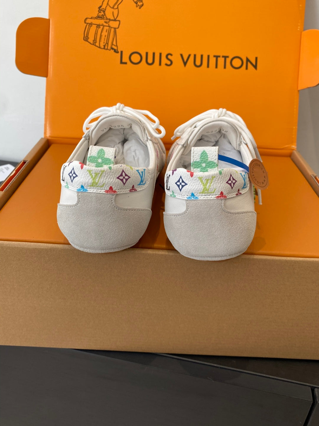 Two white unisex sneakers with multicolor logo trim at the heel and lace-up tops