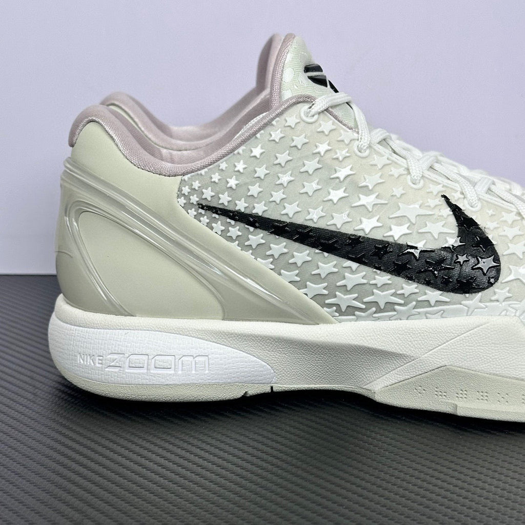 Low-top basketball sneaker, white star-pattern upper, black swoosh, padded heel collar