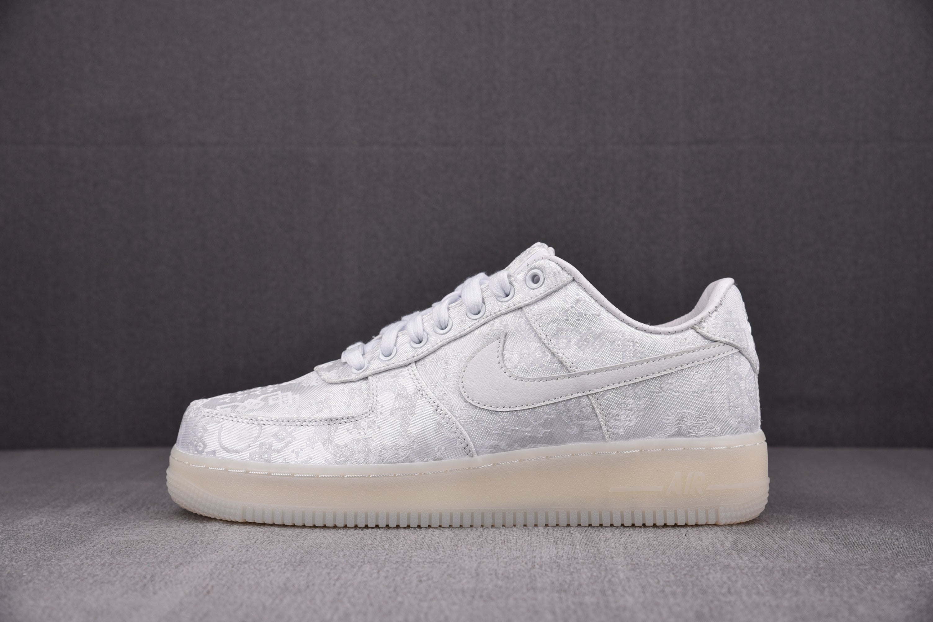 White low-top sneakers with lace-up front and embossed logo pattern