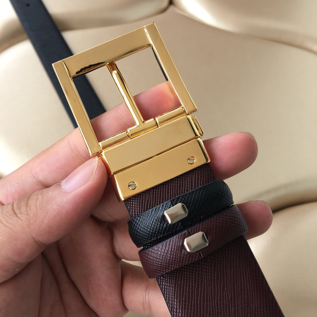 Leather belt buckle close-up, gold hardware on black and maroon strap