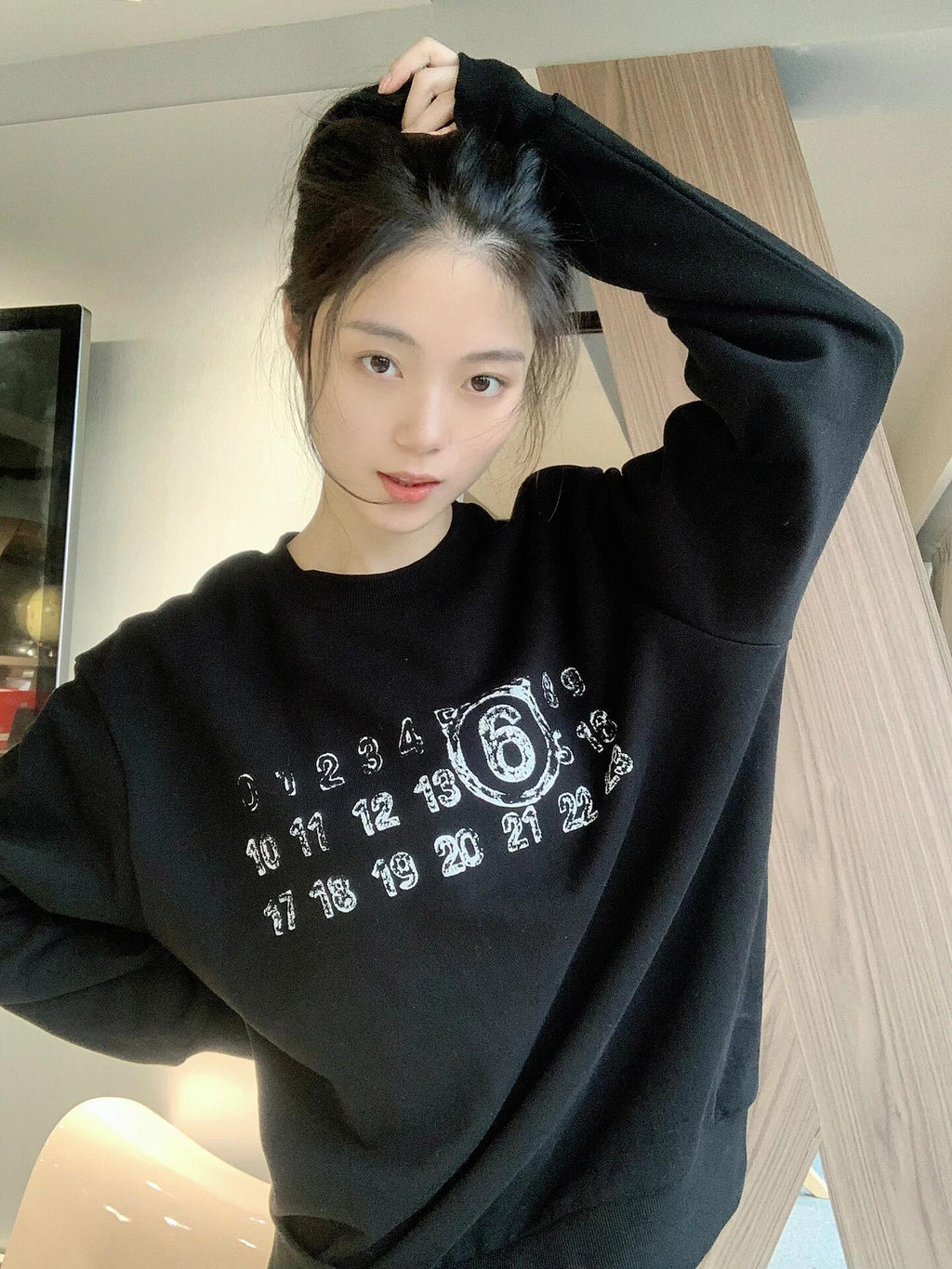 Black crewneck sweatshirt with white number and '6' graphic print on model