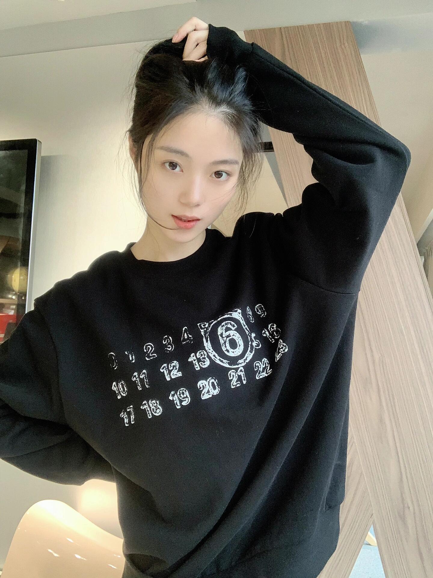 Black crewneck sweatshirt with white number and '6' graphic print on model