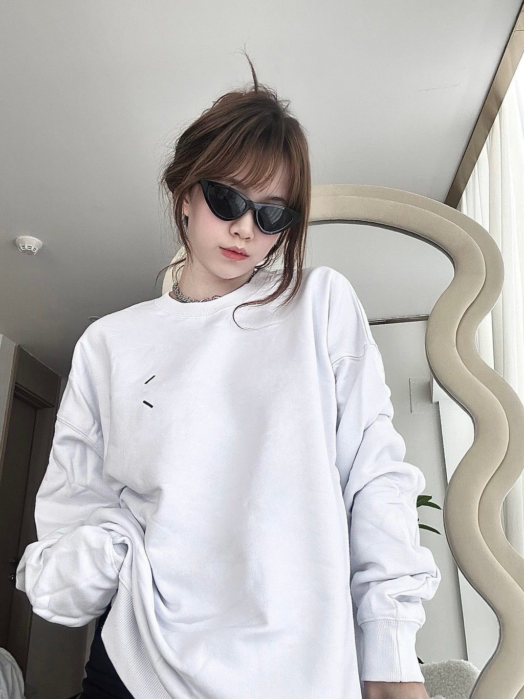 White crewneck sweatshirt worn, small chest graphic and long sleeves