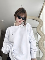 White crewneck sweatshirt worn, small chest graphic and long sleeves