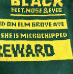 Green knit sweater closeup with yellow “BLACK” lettering and band