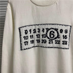 Cream knit sweater close-up of black-and-white number graphic across chest