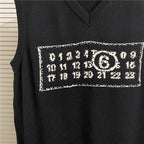 Dark sleeveless knit top with rectangular graphic patch featuring circular emblem