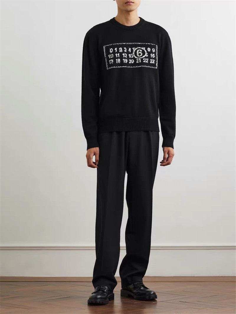 Black knit sweater with ribbed crew neck and number graphic chest, worn with black pants