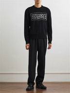 Black knit sweater with ribbed crew neck and number graphic chest, worn with black pants