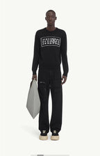 Black knit sweater with ribbed crew neck and number graphic chest, styled with black pants