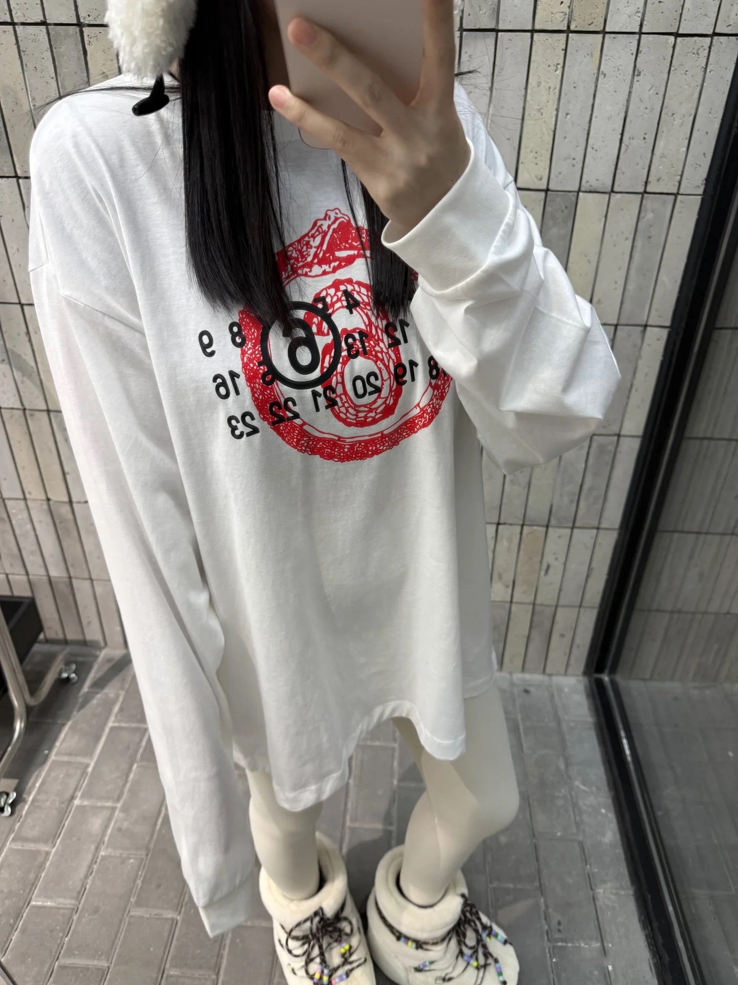 White long-sleeve T-shirt with red emblem graphic, worn by model