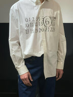 White button-up shirt with black number graphic on chest; cuffs and buttons visible