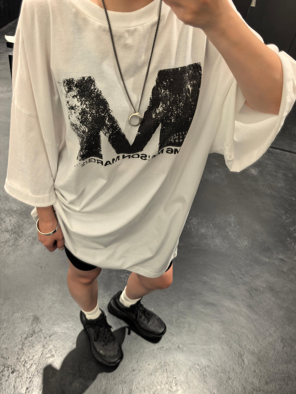 White graphic T-shirt with distressed M logo, worn by model