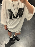 White graphic T-shirt with distressed M logo, worn by model