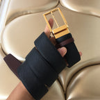 Prada belt with gold buckle and dark textured strap, fold-over ends shown.