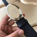 Prada belt buckle close-up with embossed branding on dark textured strap