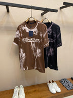 Two graphic T-shirts on hangers: brown with white splatter and dark with purple splatter