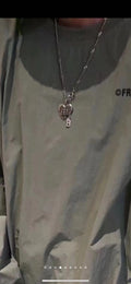 Silver chain necklace with heart pendant charm, worn on a dark top