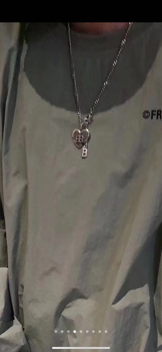 Silver chain necklace with heart pendant charm, worn on a dark top