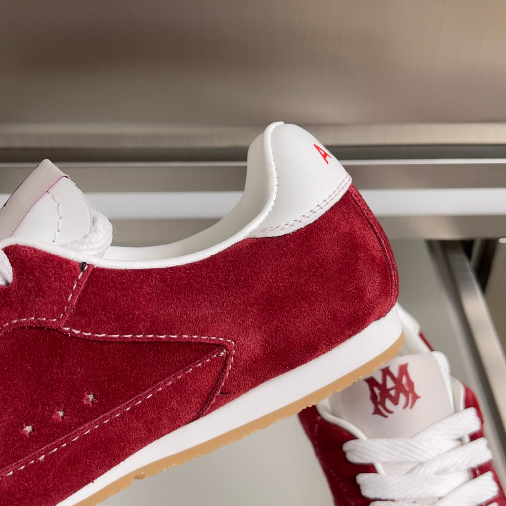 Amiri red suede sneaker close-up, white laces, side stitching, logo on heel tab