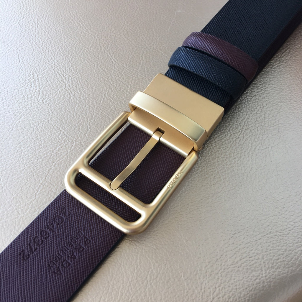 Leather belt buckle detail with gold-tone frame on dark blue and burgundy strap