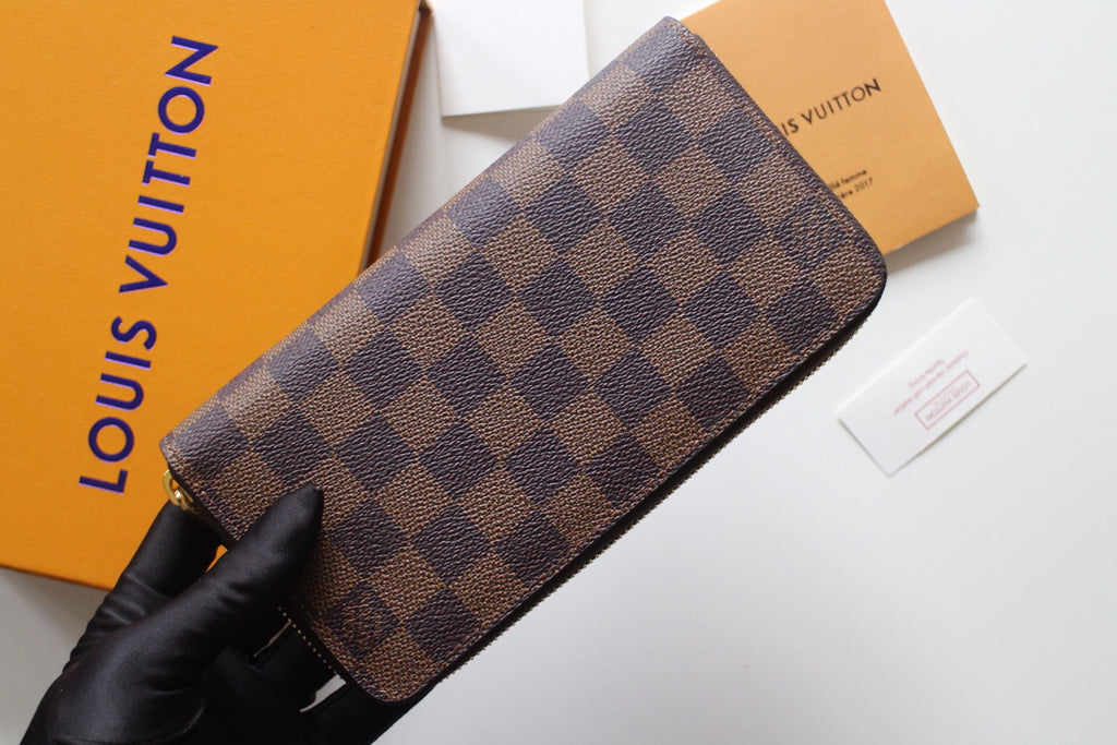 Louis Vuitton small bag with Damier check canvas and curved zip opening.