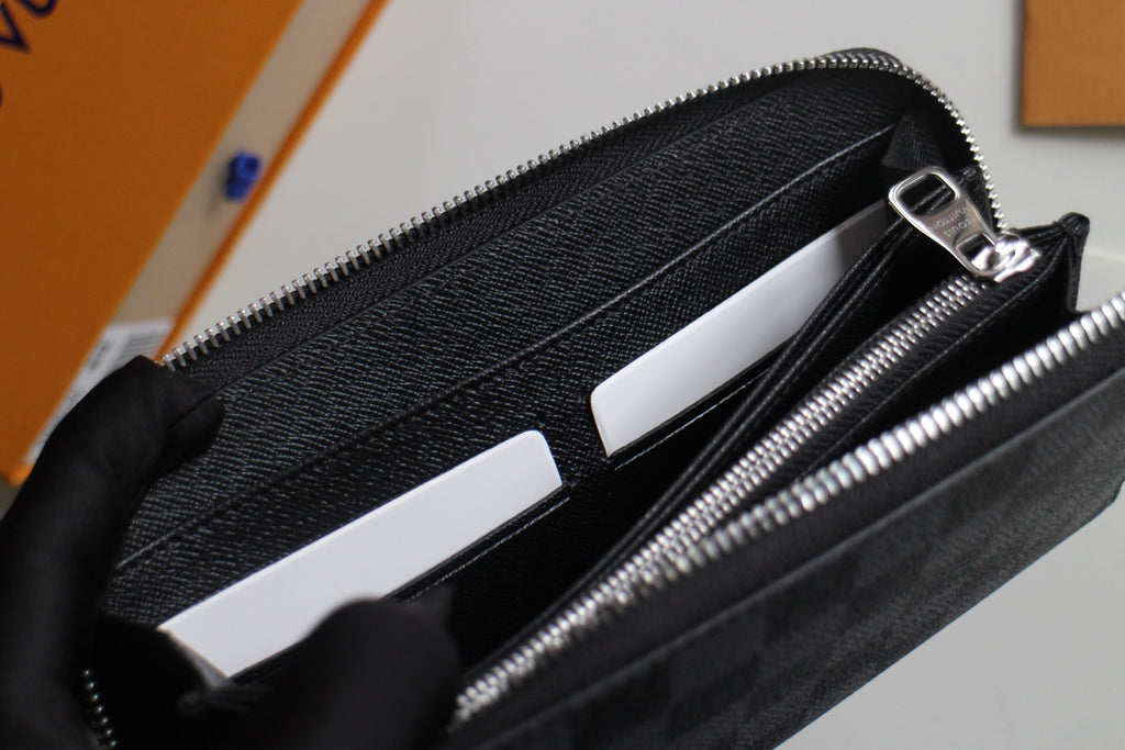 Small Louis Vuitton zip wallet open, showing card slots and inner black lining.