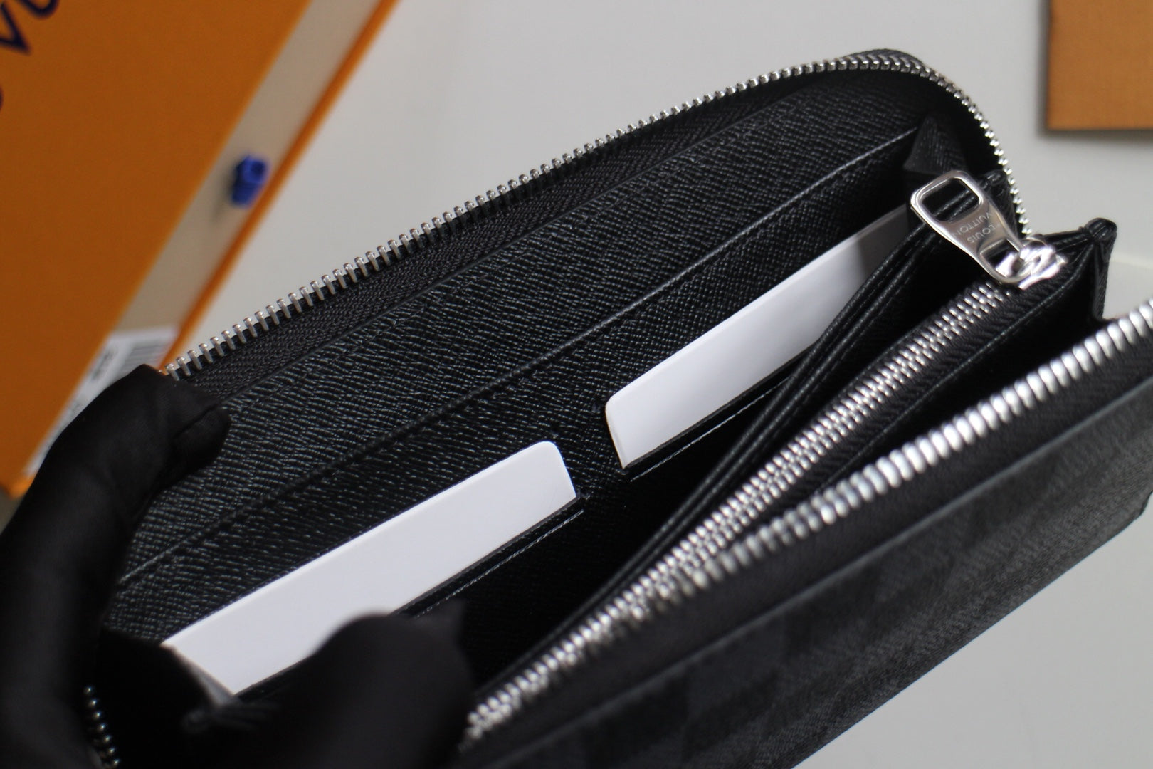 Small Louis Vuitton zip wallet open, showing card slots and inner black lining.