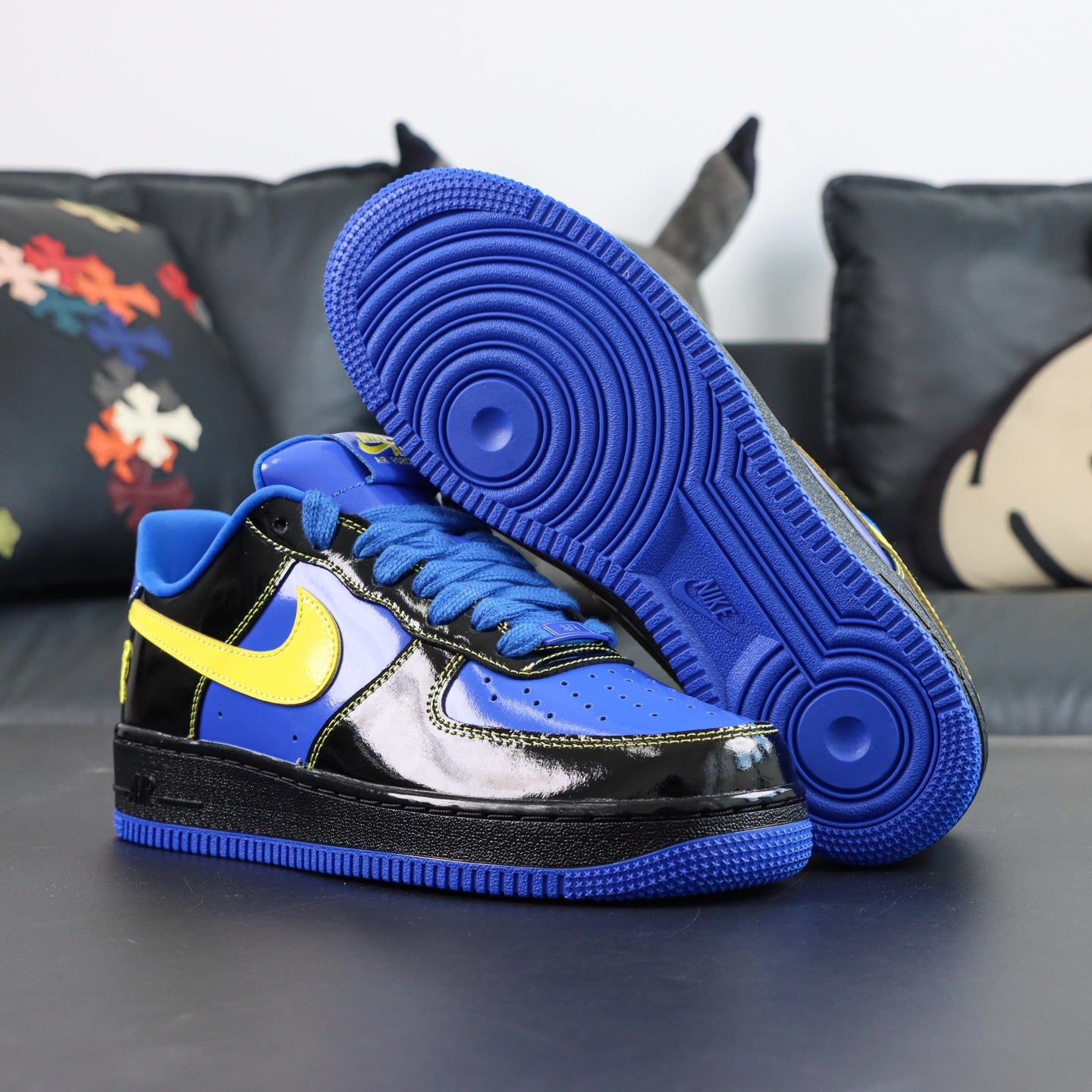 Nike Air Force 1 low-top sneakers, blue and black with yellow Swoosh; side profile and outsole.