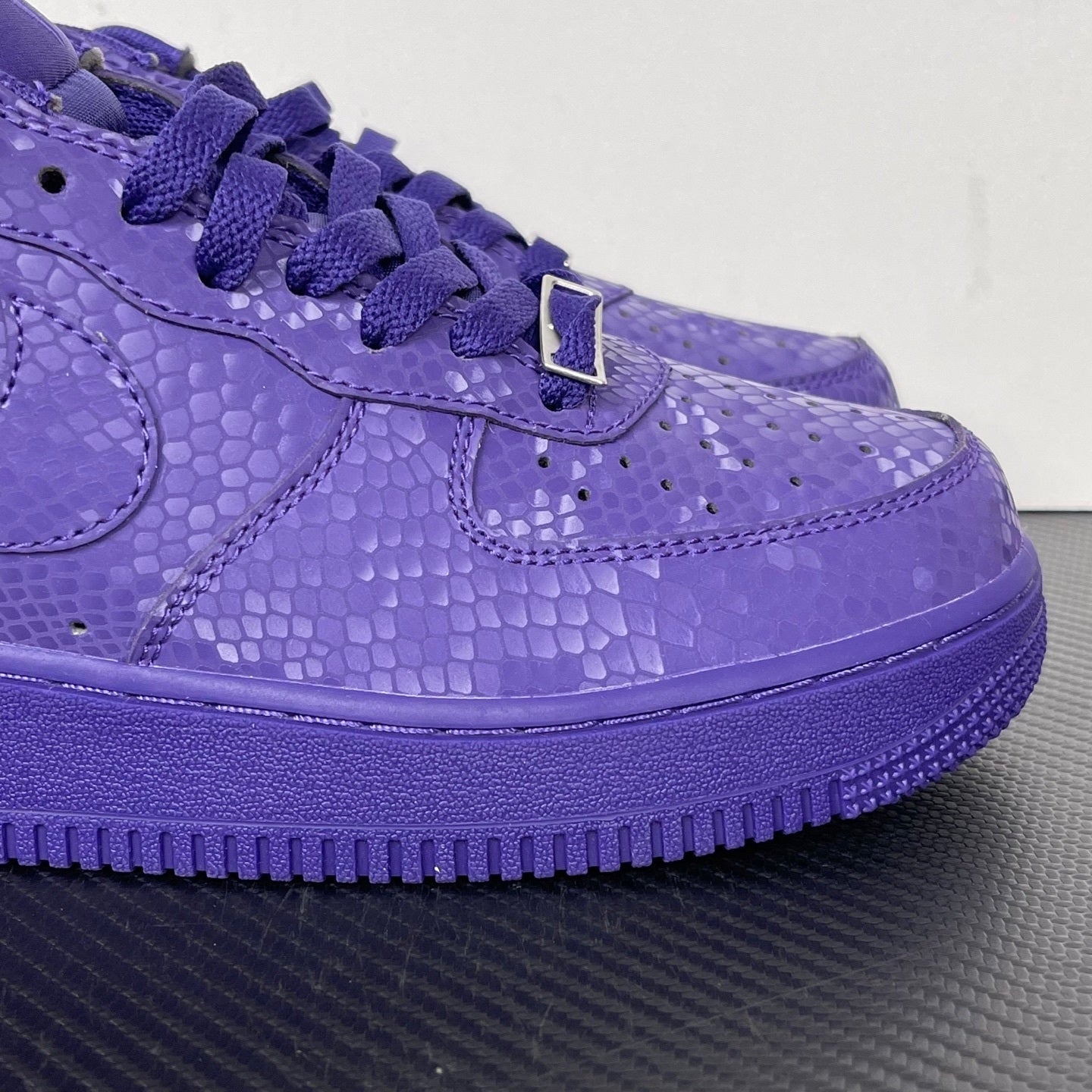 Purple low-top sneakers with lace-up closure, strap detail, and textured upper
