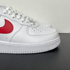 White low-top sneakers, red Nike swoosh detail and perforated toe, lace-up.