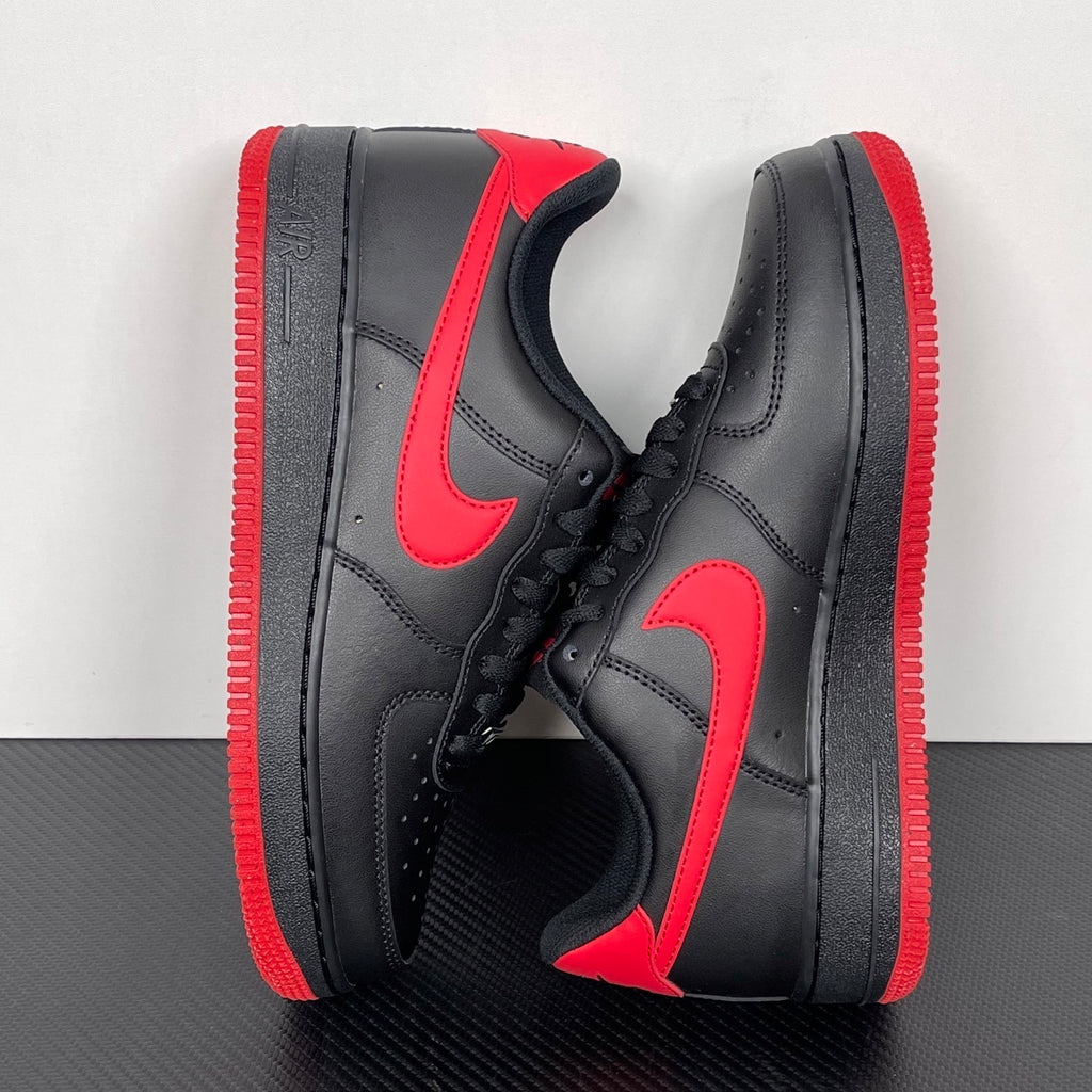 Black and red low-top sneakers with red swoosh and matching red rubber sole