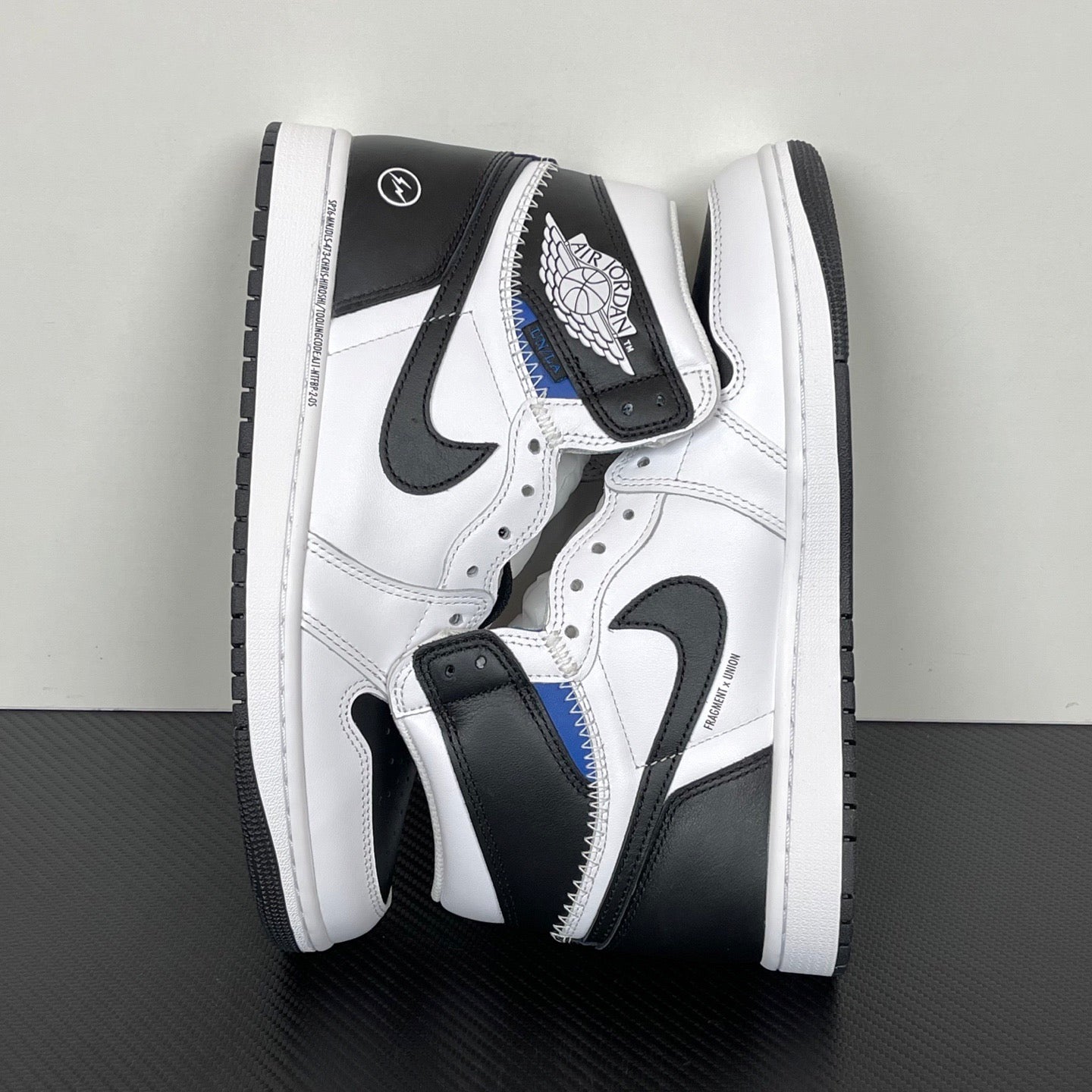 Back/side view of white and black high-top sneakers with black heel tabs and blue trim