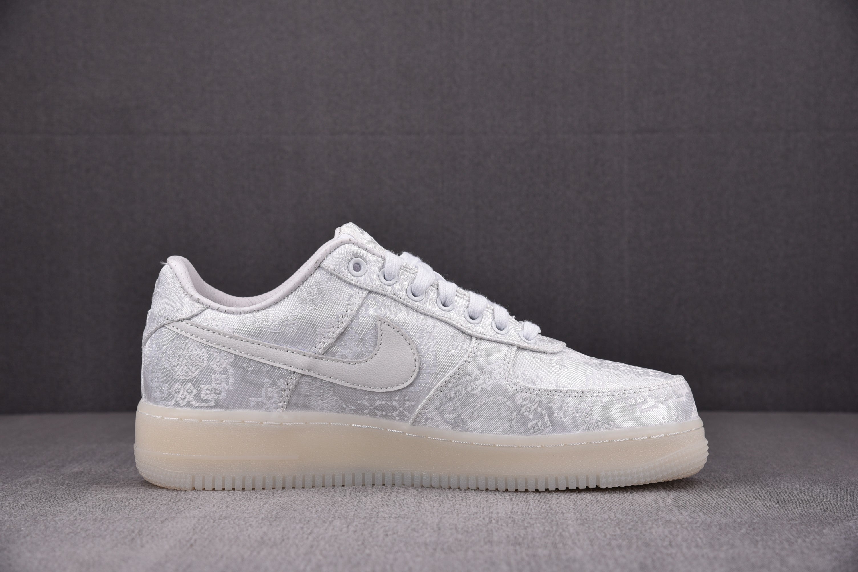 White low-top sneakers side view with swoosh and embossed pattern
