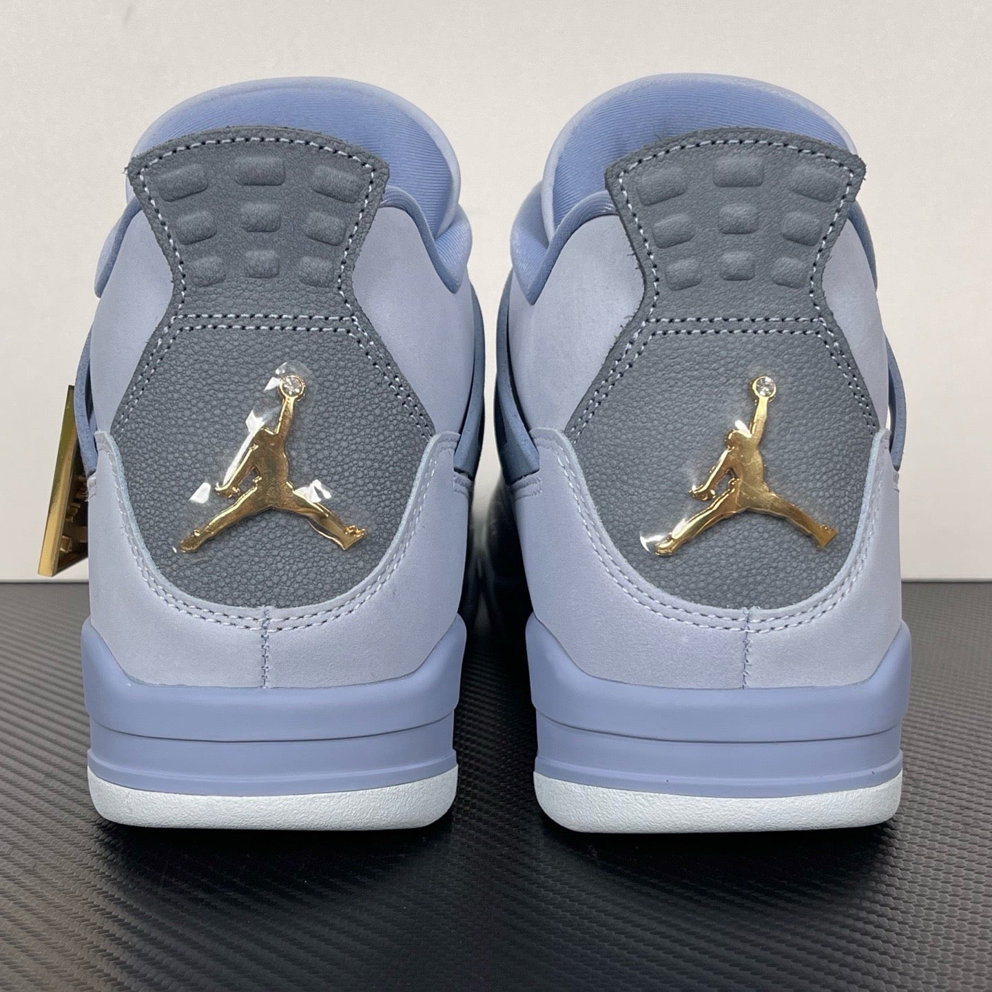 Pair of light blue Air Jordan 4 sneakers with gold Jumpman on heel