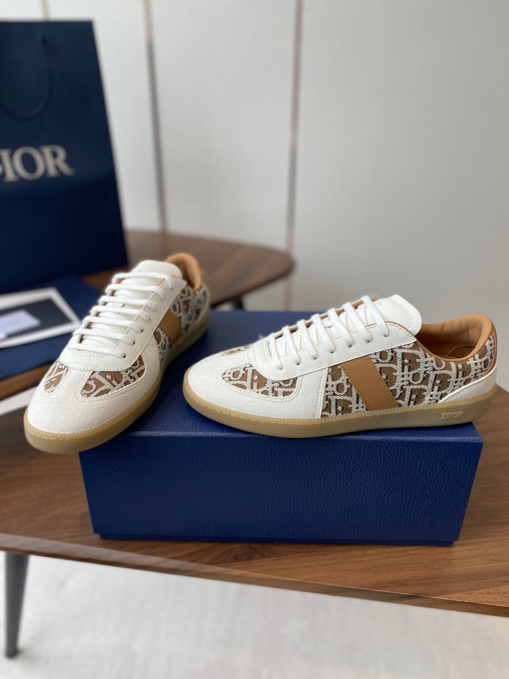 Two Dior unisex sneakers in white with tan monogram side panels and white laces