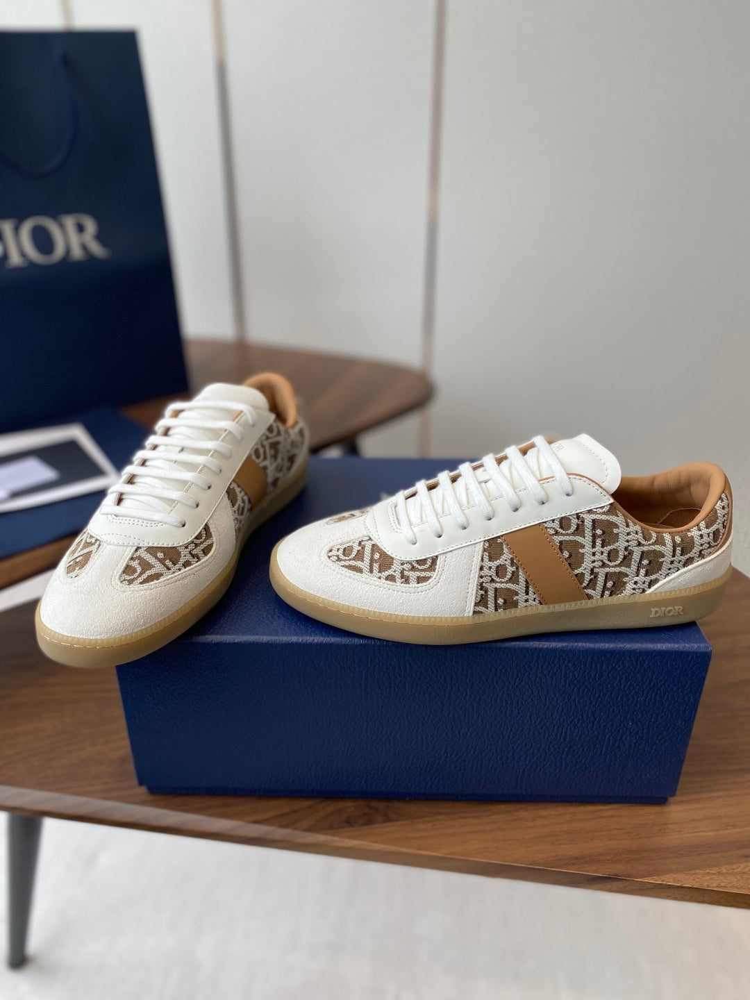 Two Dior unisex sneakers in white with tan monogram side panels and white laces