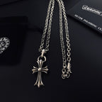 Silver cross pendant with linked chains displayed on a black card