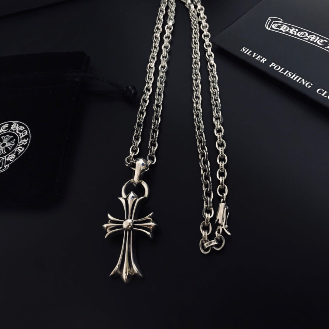 Silver cross pendant with linked chains displayed on a black card