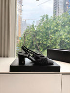 Black Chanel slingback heels with openwork texture, side angle on box