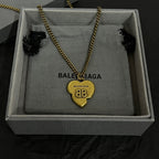 Heart pendant necklace with gold chain and logo heart charm, in a gray box.