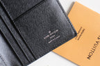 Small Louis Vuitton black textured cardholder close-up with printed LV branding