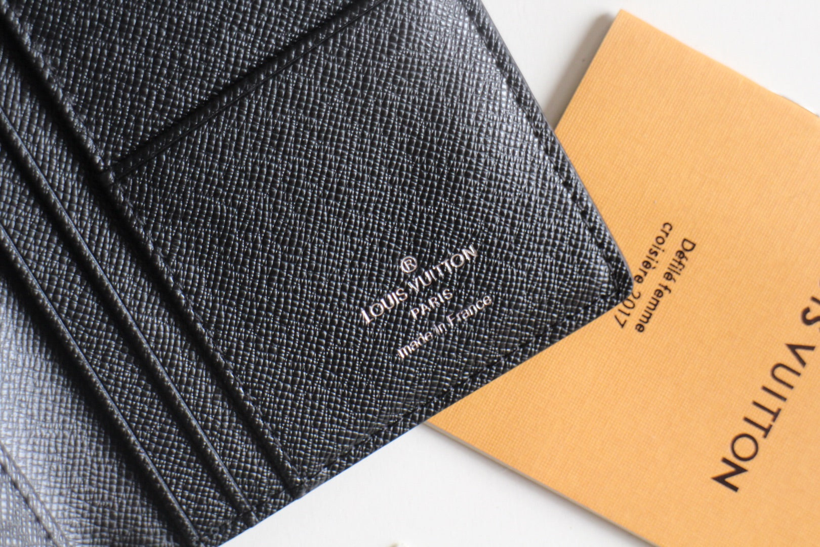 Small Louis Vuitton black textured cardholder close-up with printed LV branding