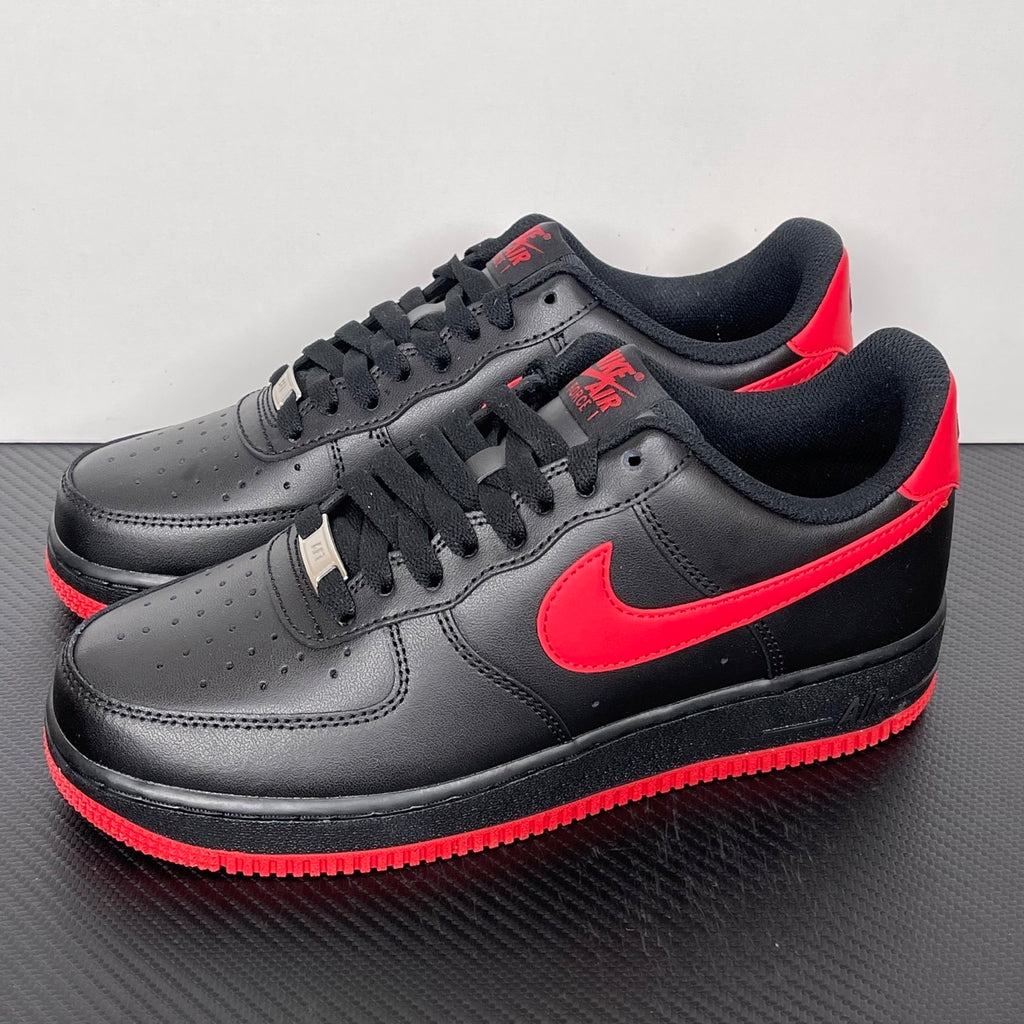 Black low-top sneakers with red swoosh, black laces, and red outsole edge