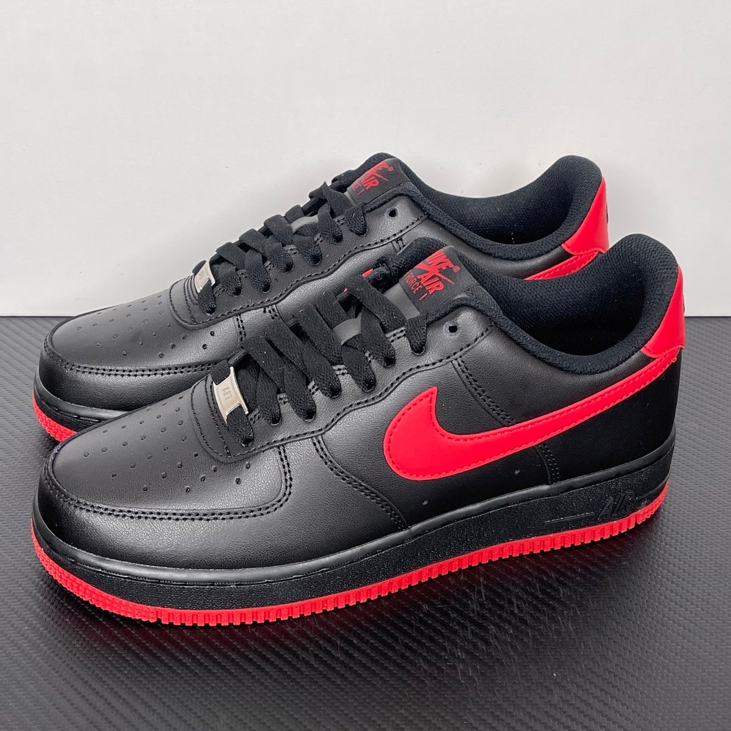 Black low-top sneakers with red swoosh, black laces, and red outsole edge