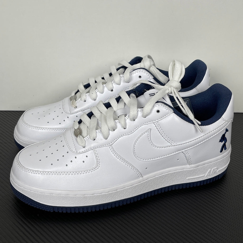 White Nike Air Force 1 lace-up sneakers with navy accents and swoosh detail