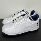 White Nike Air Force 1 lace-up sneakers with navy accents and swoosh detail
