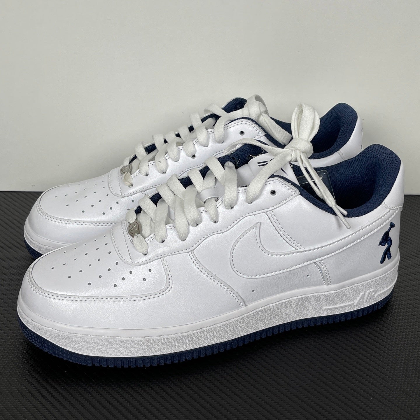 White Nike Air Force 1 lace-up sneakers with navy accents and swoosh detail