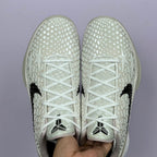 Low-top sneaker toe view, white star-pattern upper, black swoosh accents, white laces